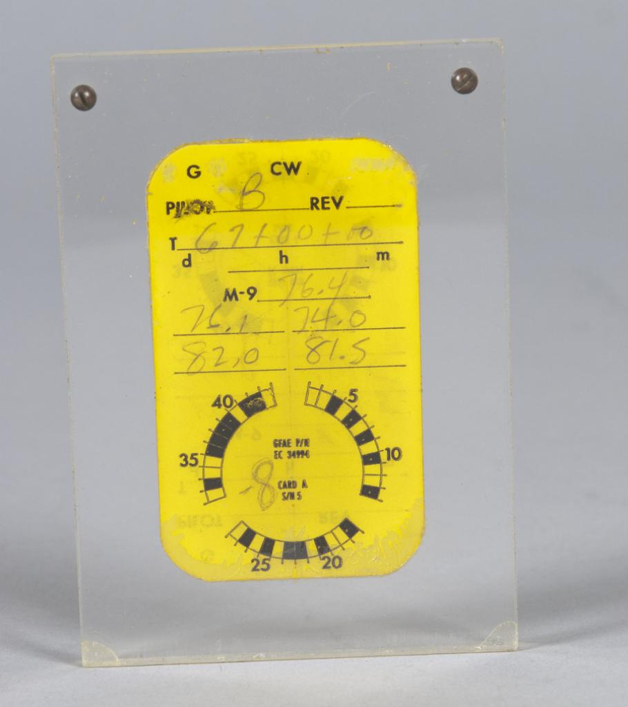 A small rectangular yellow card incased between two pieces of clear plastic. The area at the top of the card denoting the pilot name is marked with a B, presumably for Frank Borman. The rest of the card has different numbers recorded related to different optical measurements.