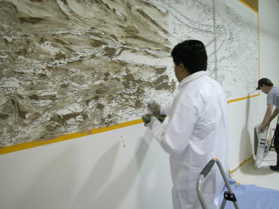 A man paints with mud on a wall