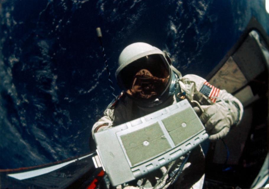 Astronaut in spacesuit on a spacewalk holding a box-shaped item.