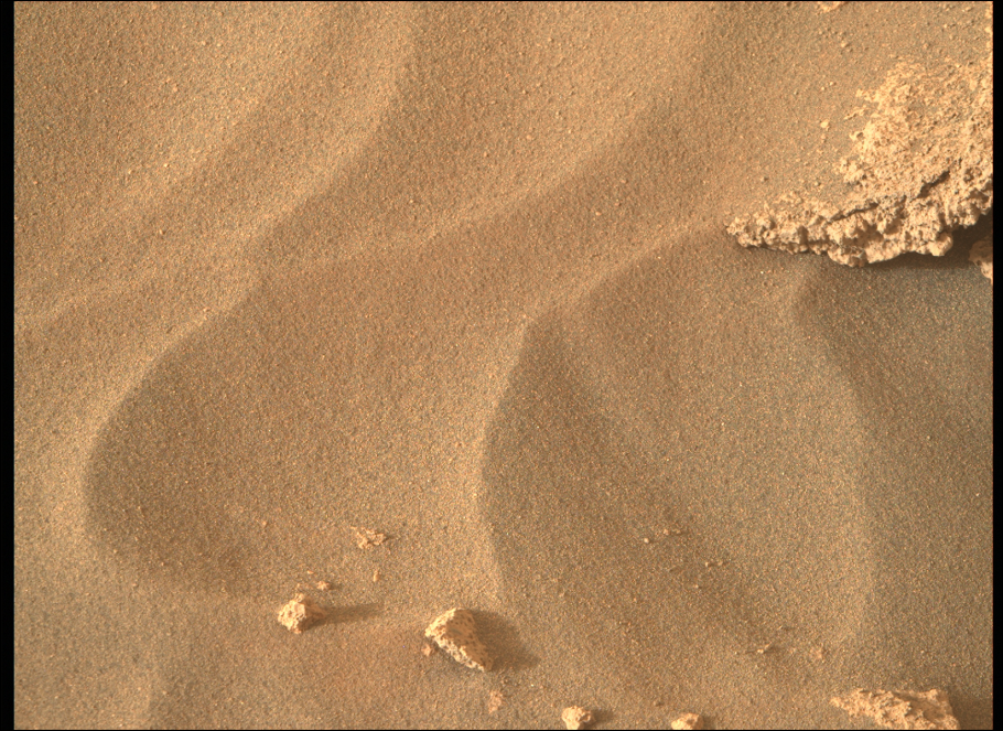 Surface of Mars with ripples in the sandlike material on its surface.