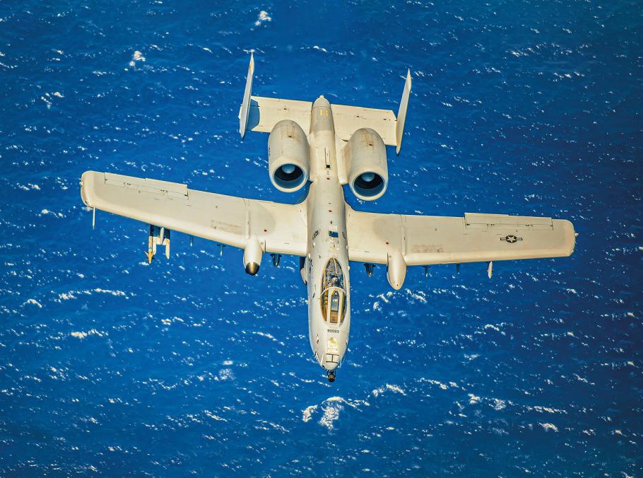 The khaki coloring of a Fairchild Republic A-10C Thunderbolt II is contrasted against deep blue as it flies over the ocean.