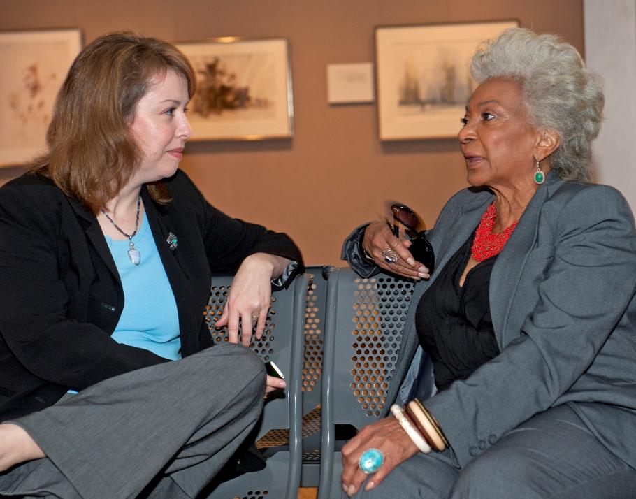 Margaret Weitekamp and Nichelle Nichols sit on a metal bench an talk to one another
