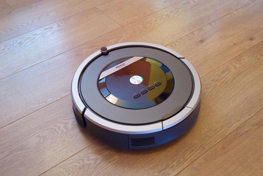 A small circular disk-like vacuum on a wooden floor. 