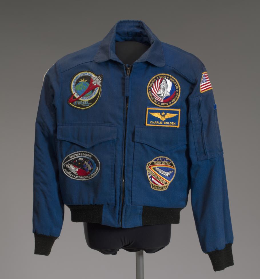 A blue NASA flight jacket covered in various mission patches.