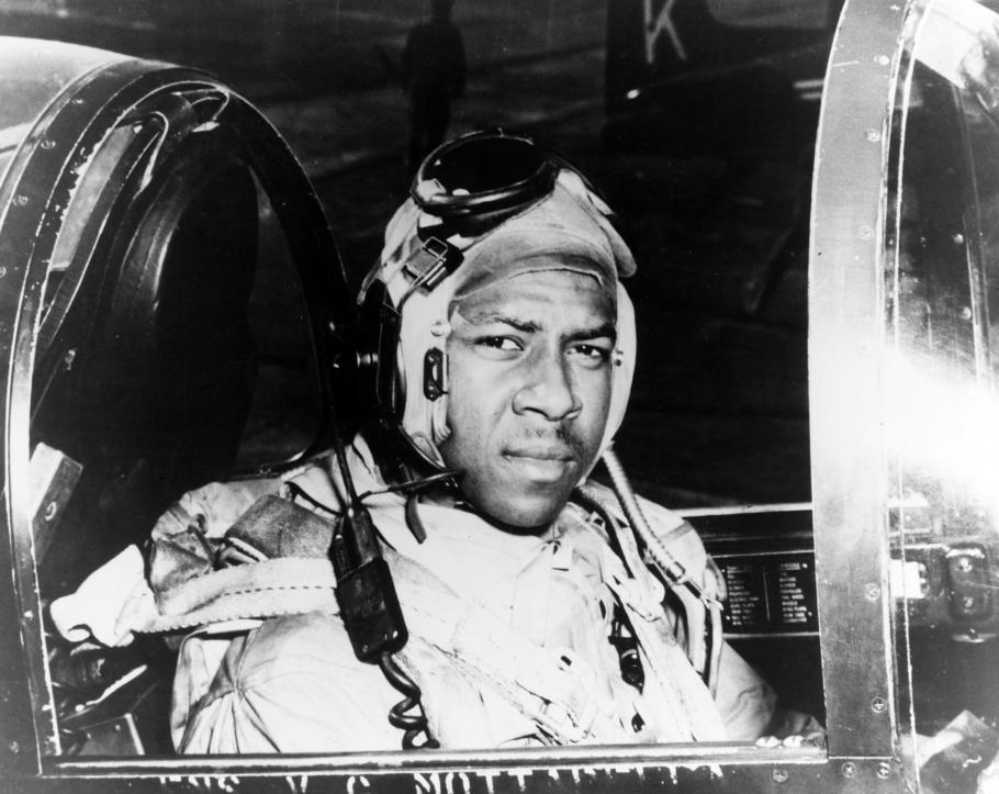 Jesse Leroy Brown looks toward the camera as he sits at the controls of an aircraft.