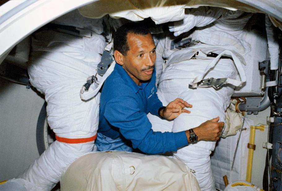 A man floats through two space suits aboard the Space Shuttle.