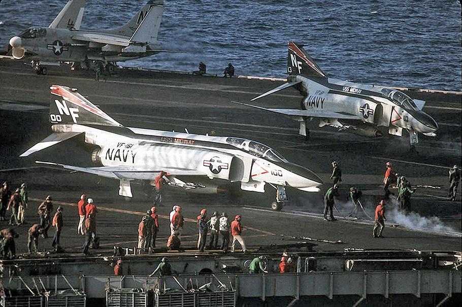 Two F-4s from VF-161 sit on the deck of the USS Midway, sailing in the Gulf of Tonkin on May 12, 1972. Flight crew attend to one of the F-4s as steam rises from the deck.