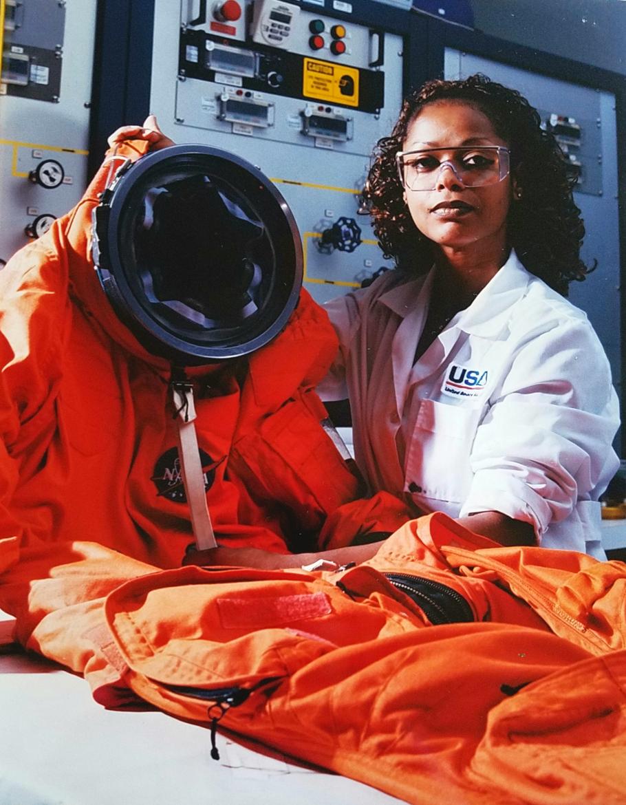 A woman holds up an orange spacesuit