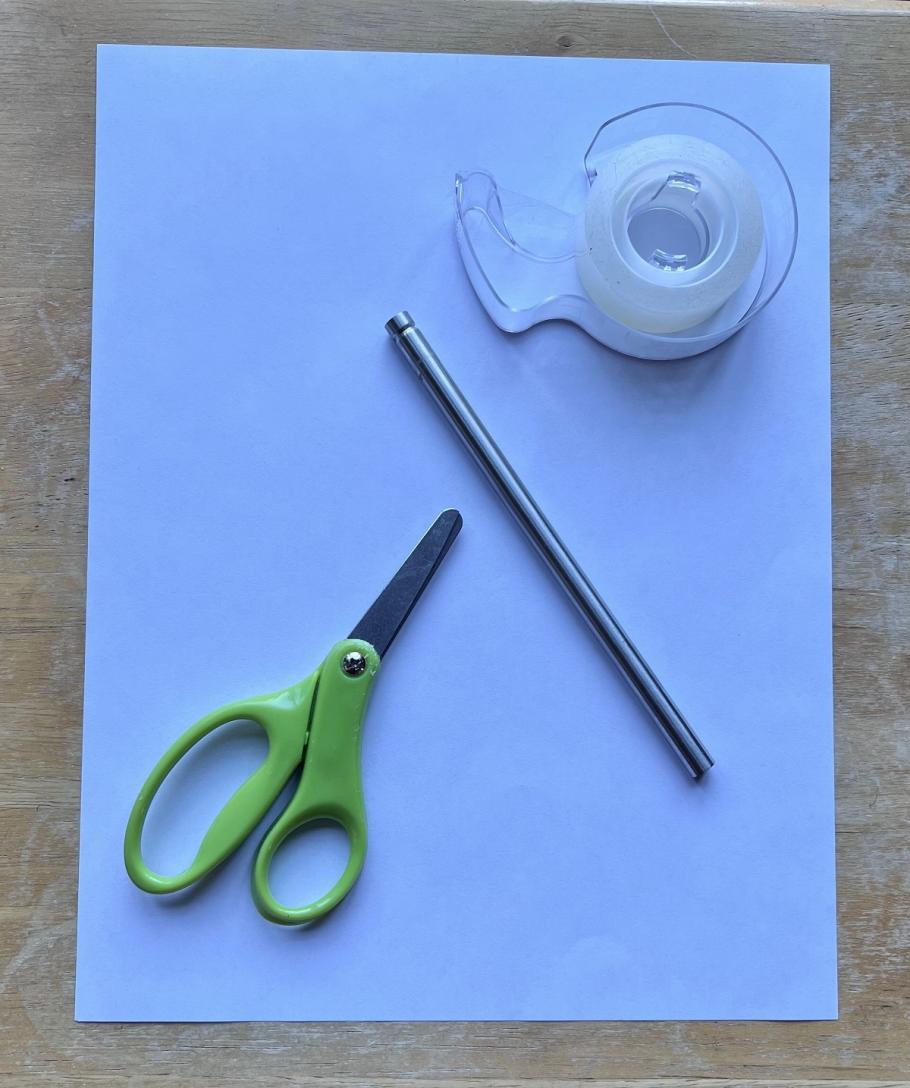 A piece of paper with scissors, tape, and a small rod on top of it. 
