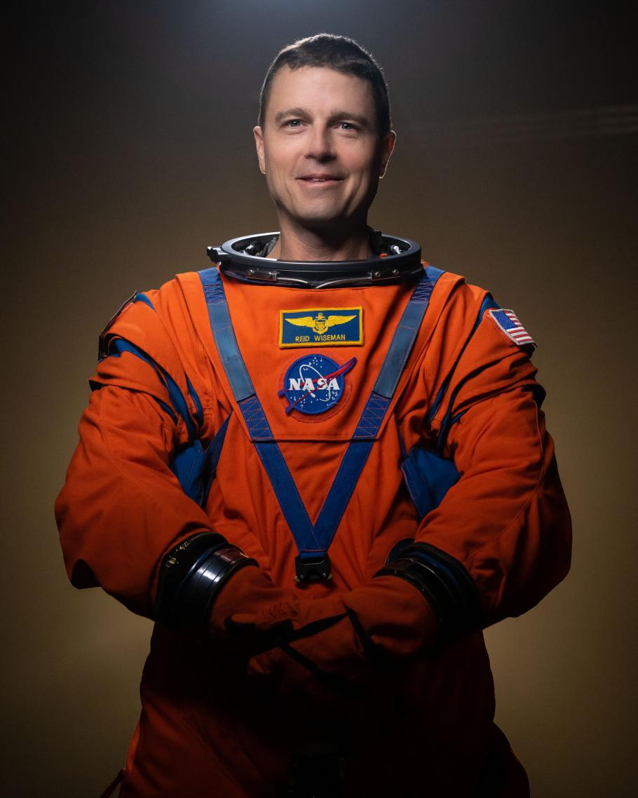 Reid Wiseman wearing an orange astronaut flight suit