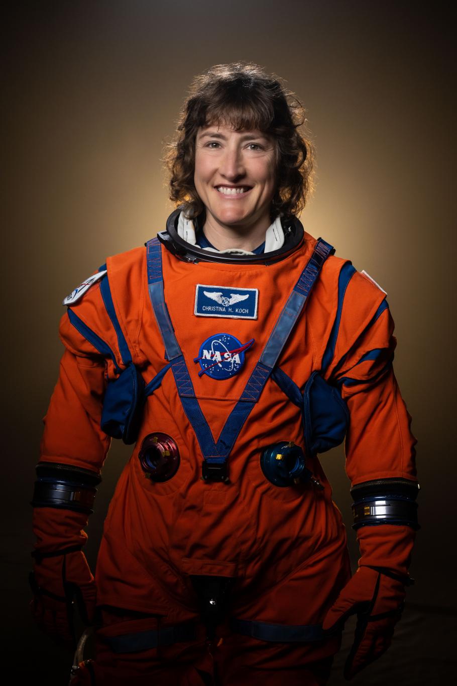 Christina Koch wearing an orange Artemis flight suit 