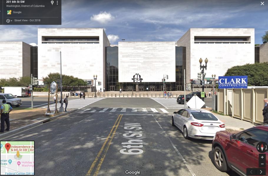 The image is captured in the middle of a street that leads directly to the entrance of a museum building.