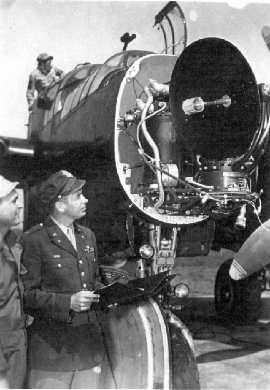Black and white image of man in uniform looking at nose of an aircraft.