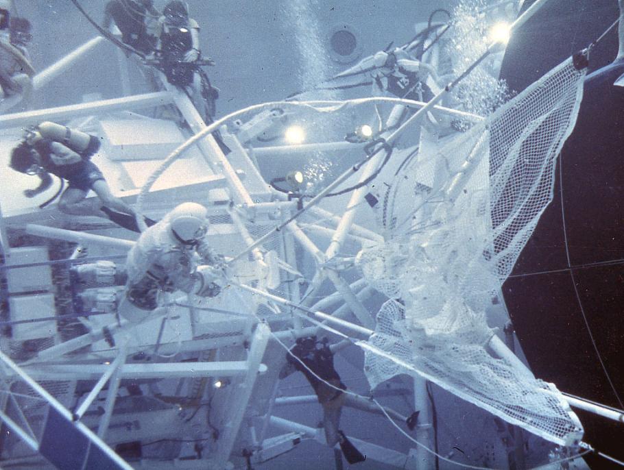 Astronauts and divers underwater working on a space simulator
