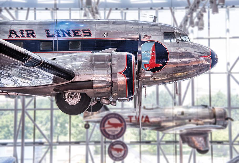View of the “America by Air” gallery hanging aircraft, showing the Eastern Airlines Douglas DC-3, a large silver aircraft with blue and orange embellishment on the side, at the Smithsonian National Air and at Space Museum in Washington, DC. 
