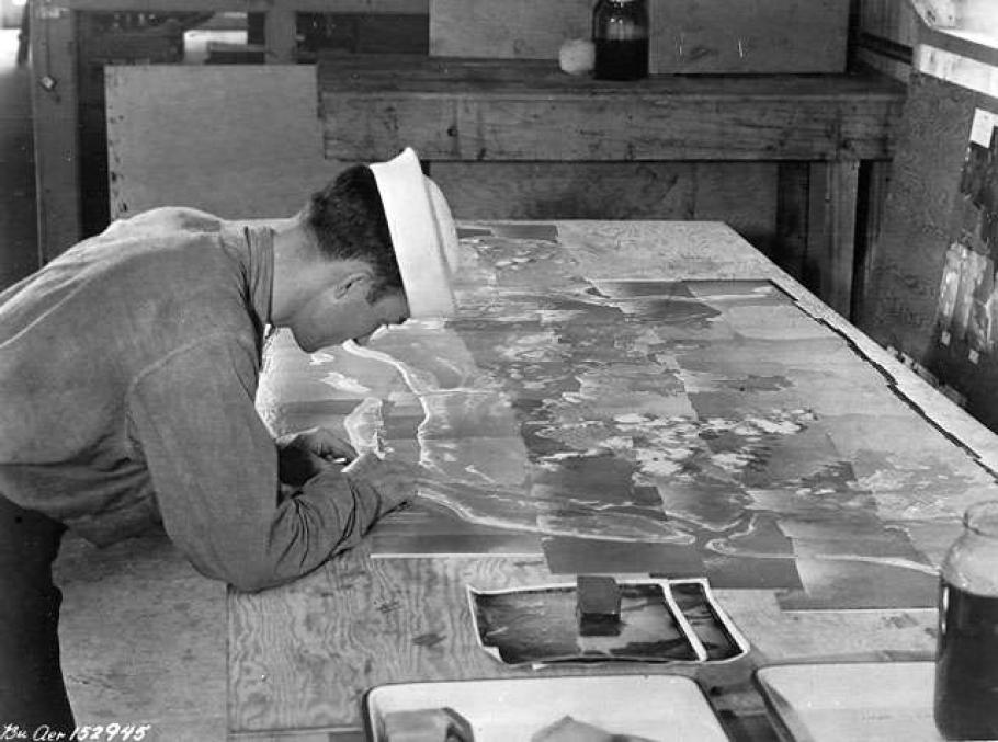 A photo of a person inspecting a large array of photos that have pieced together to create one large image.