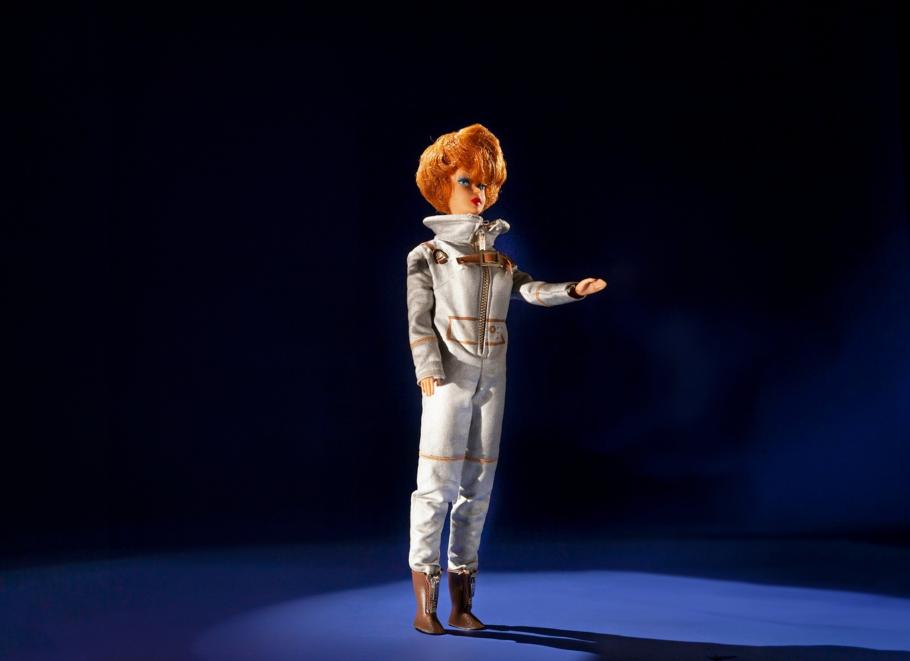 The Miss Astronaut doll photographed against a dark background. She wears a silver spacesuit and has a short haircut.