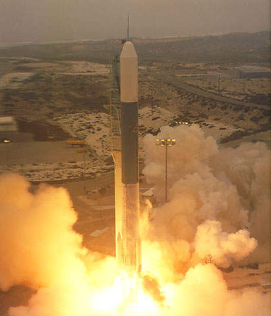 A rocket launching off from the ground. Plumes of smoke and fire combust, pushing it upward.