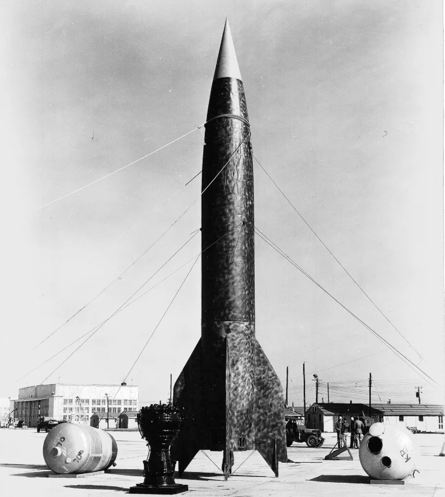 Large rocket sits in an open field.