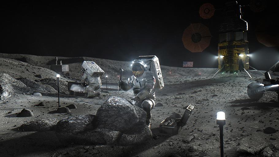 The sky is pitch black, but a series of mounted lights illuminate a patch of hilly, grey, lunar terrain where astronauts wearing bulky white spacesuits are at work.