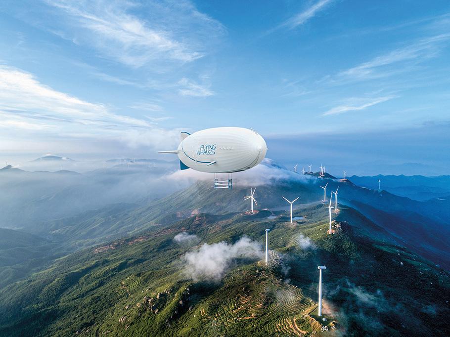 A white airship with blue fins flies over green mountaintops covered with white windmills.