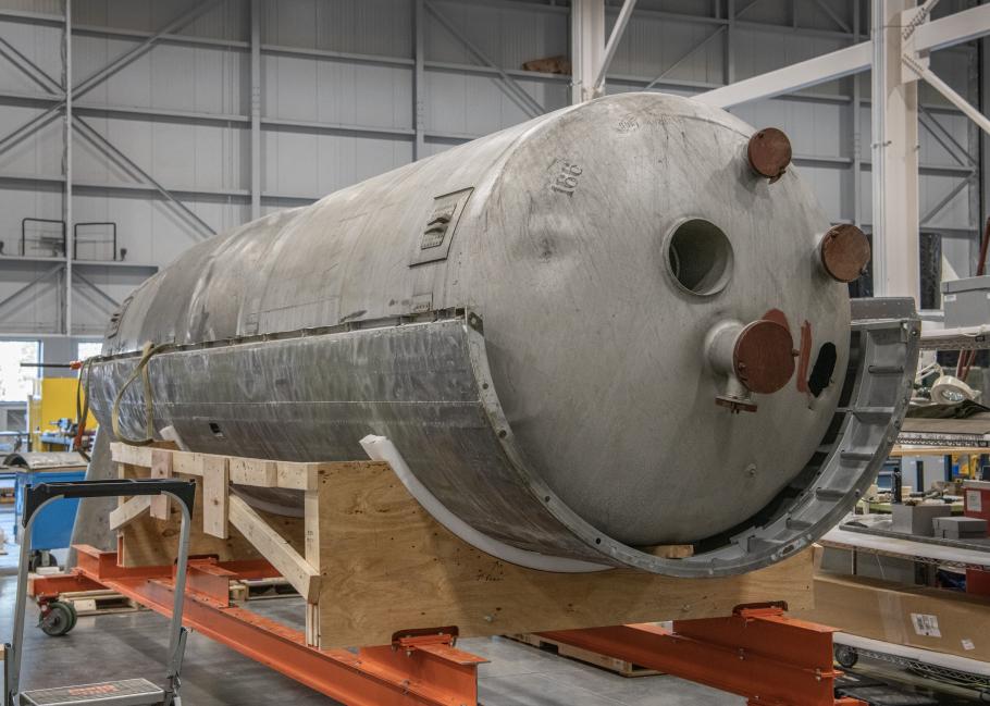 A large propellant tank sits on top of a wooden platform.