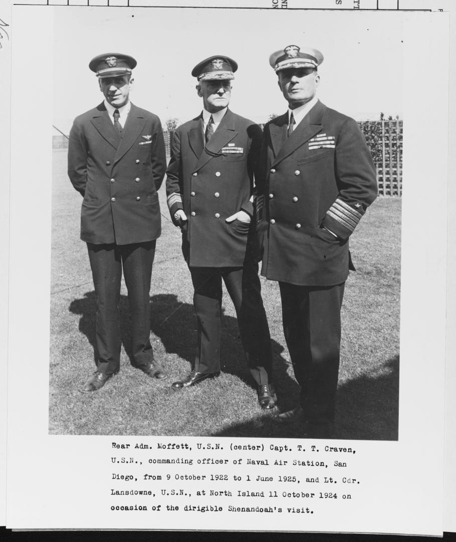 Three men standing in naval uniforms facing the camera.