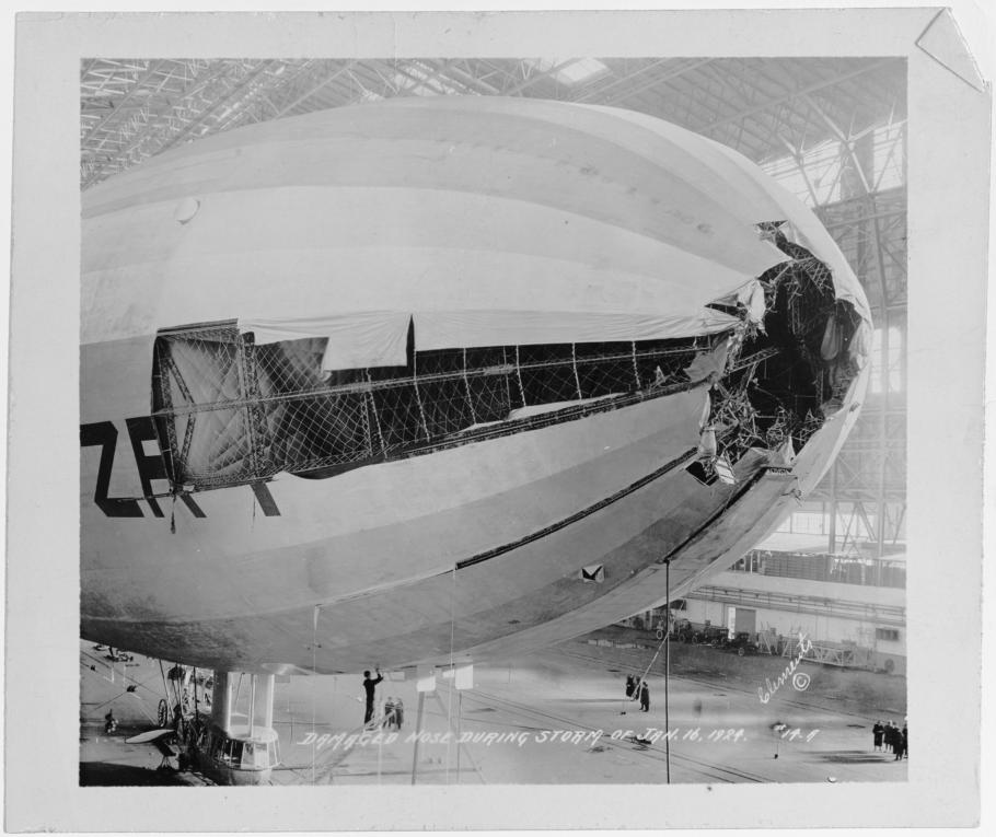 The damaged nose of an airship. The tip of the nose is entirely missing with panels of fabric ripped away down the ship's side.