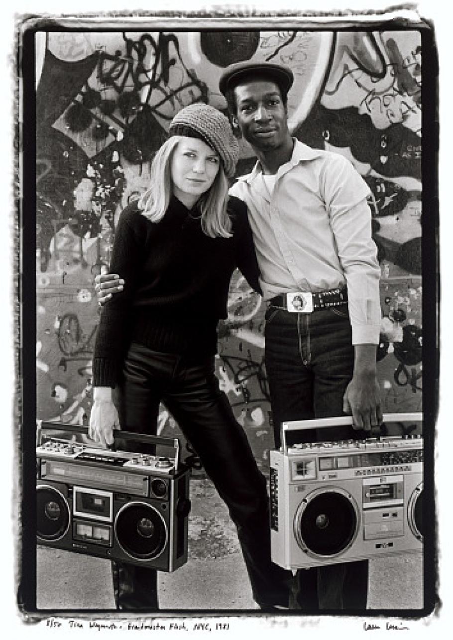 A black and white picture of two very cool looking people carrying boom boxes.  