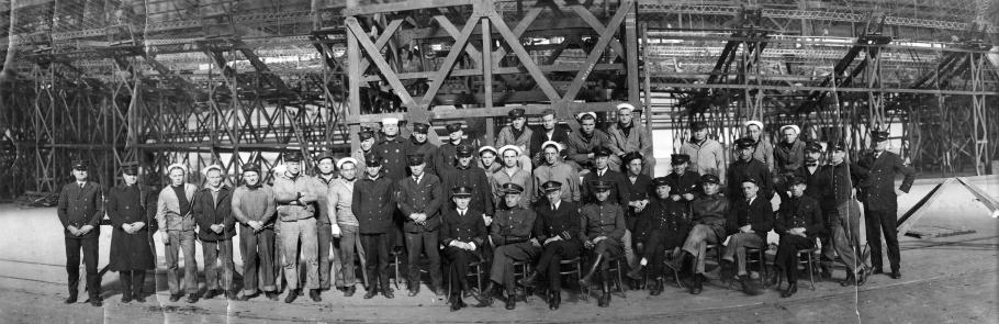 A large group of men in naval uniforms pose for a photo.