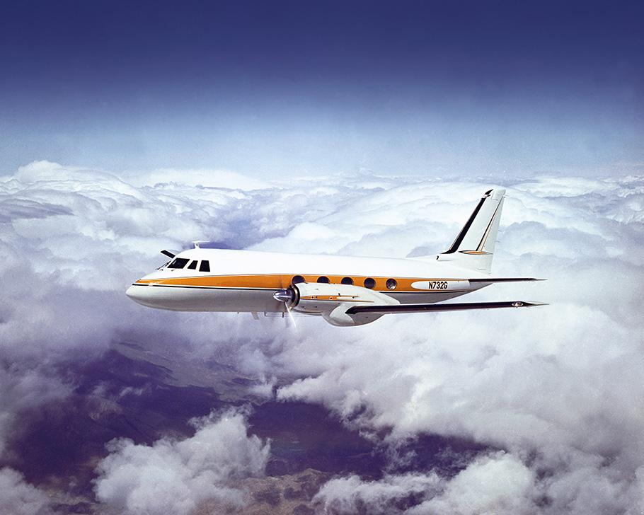A sleak Grumman Gulfstream I plane in flight. The aircraft is 64 feet in length, with five windows on the side in addition to the cockpit, and is powered by two Rolls-Royce Dart turboprop engines. It is painted 