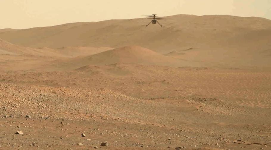 A small helicopter seen in the distance flying above the surface of Mars.