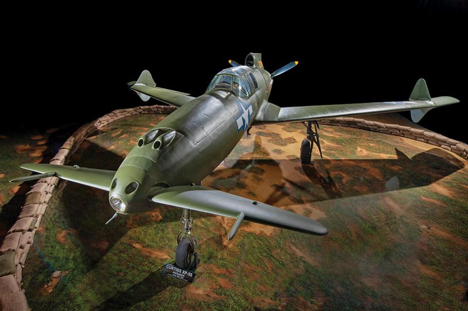 This unusual-looking aircraft, painted dark green, features two short wings on the nose, two large swept-back wings near the rear, with a propeller mounted behind the pilot's cockpit.