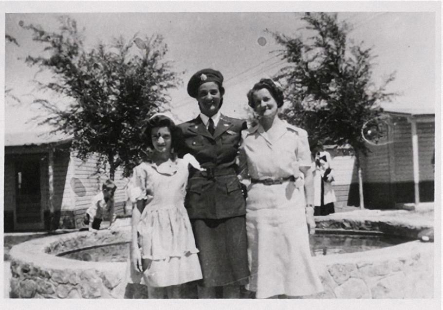 A woman in uniform poses for a picture with two other women to the left and right of her.