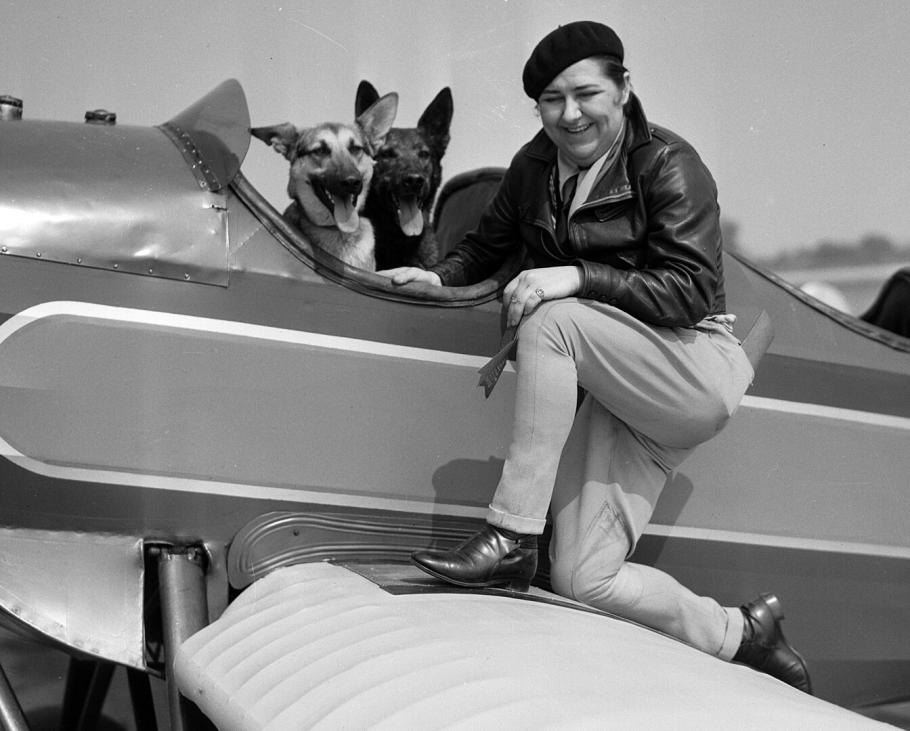 Woman poses on one knee on the wing of an aircraft.
