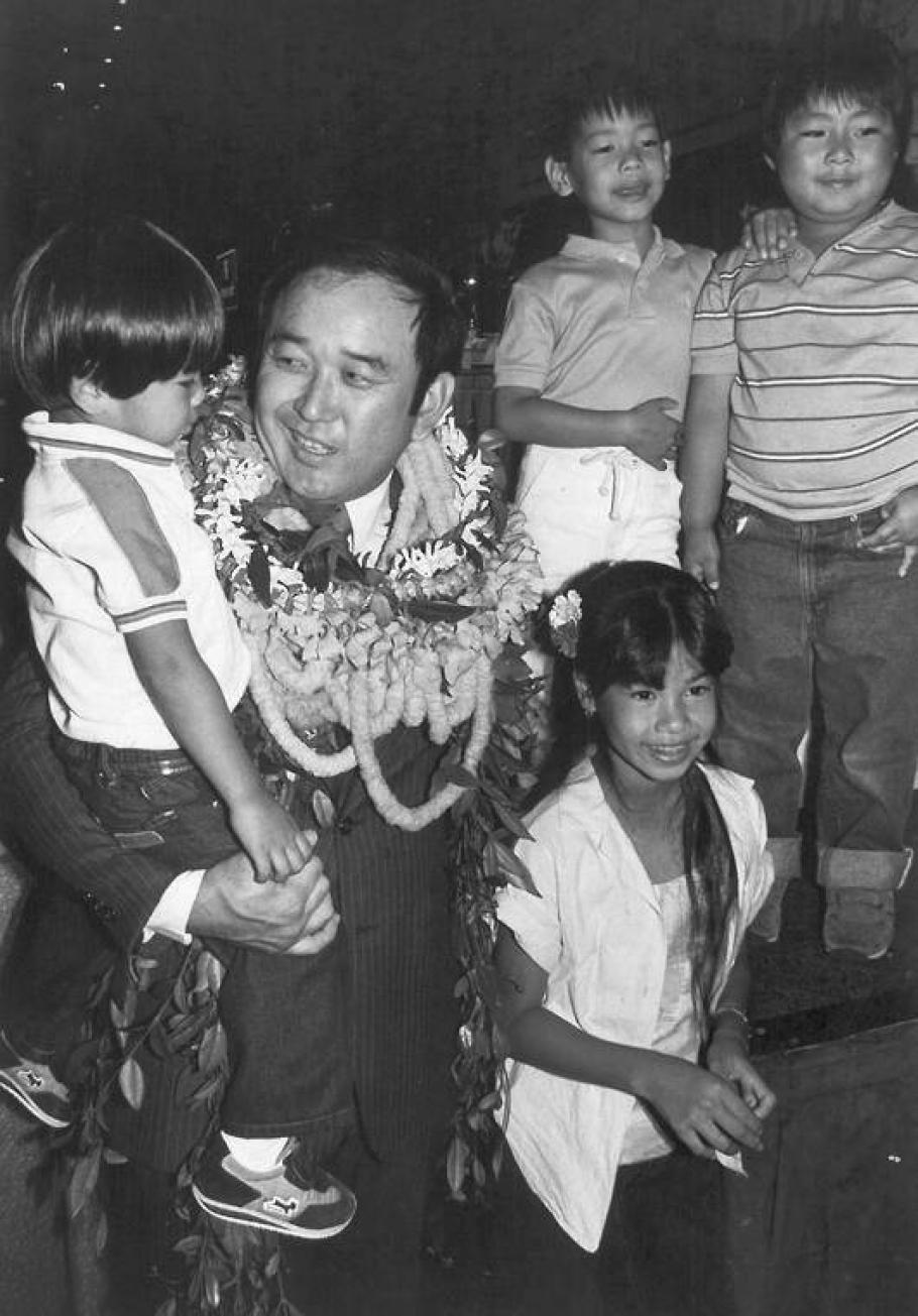Black and white image of Ellison Onizuka holding a child and other children around him.