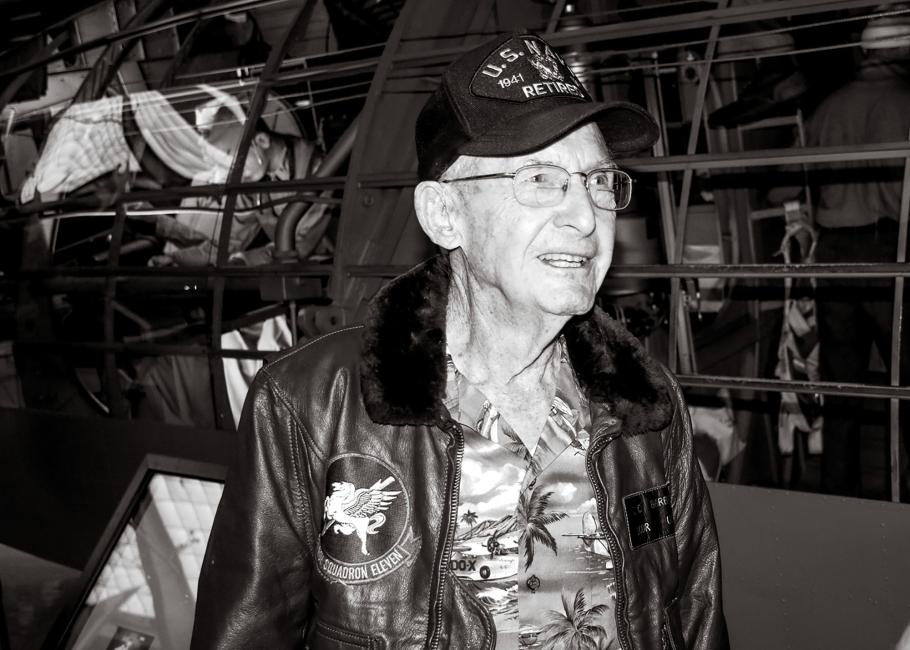 A photo of retired Lt. Cmdr. Cash Barber depicts a man, approaching 100 years old, wearing a veterans cap, a leather jacket, and a Hawaiian shirt.
