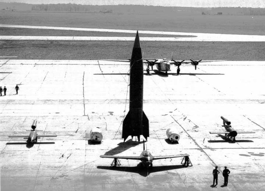 A missile stands in the middle of an airfield in a high contrast black and white image.