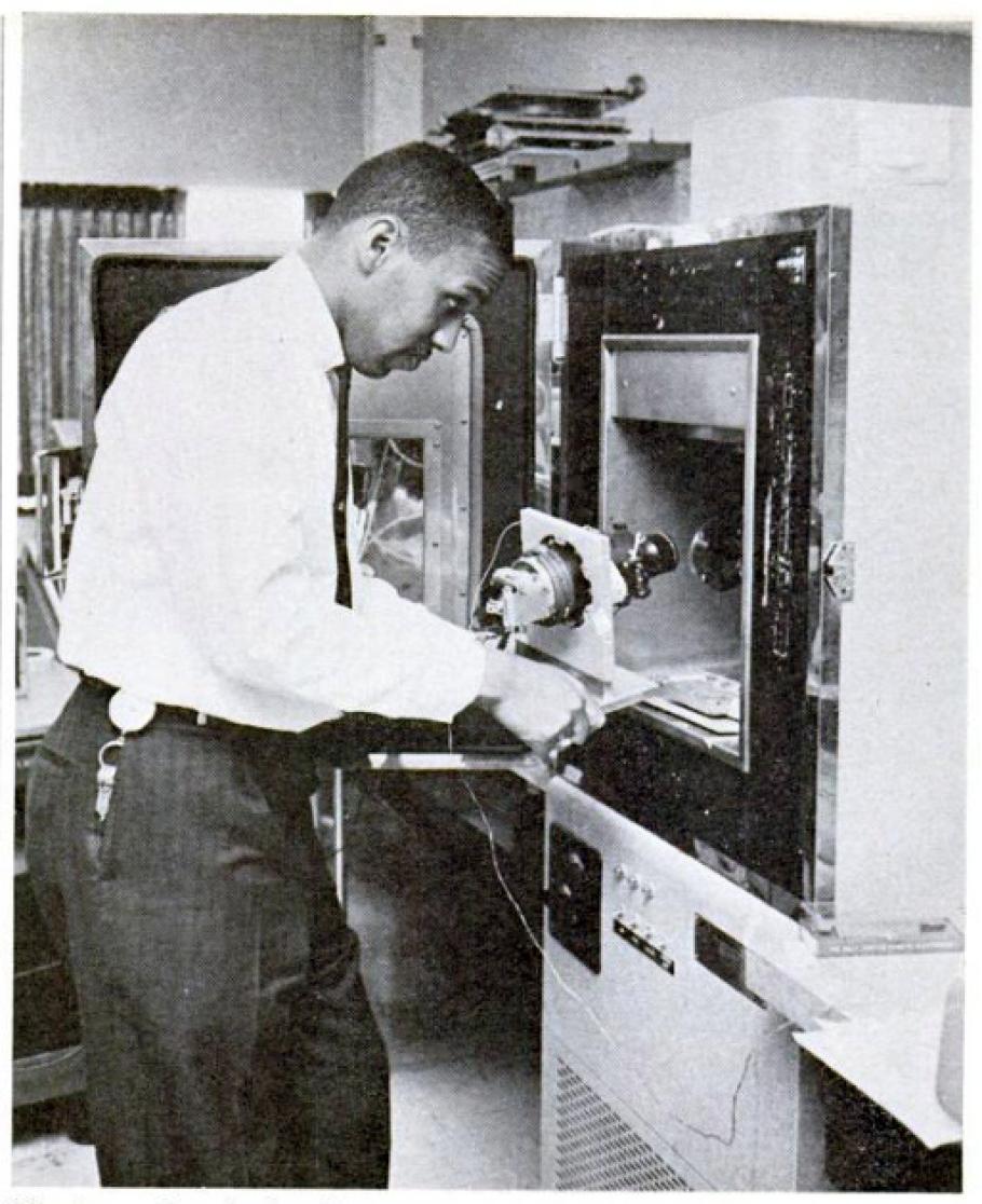 Vintage black and white image of a man conducting an experiment using scientific equipment in a laboratory setting.