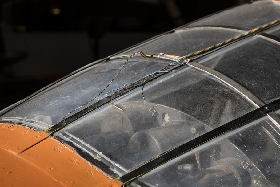 Top view of cockpit of an airplane. The airplane is painted orange and the cockpit window is closed. 