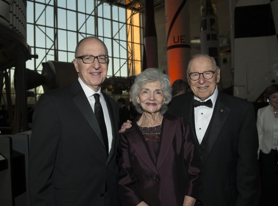 Smithsonian Secretary Dr. David Skorton, a white male, stands on the left of Mrs. Marilyn Lovell, an older white woman, and 2016 National Air and Space Museum Lifetime Achievement Award winner James Lovel, an older white man.