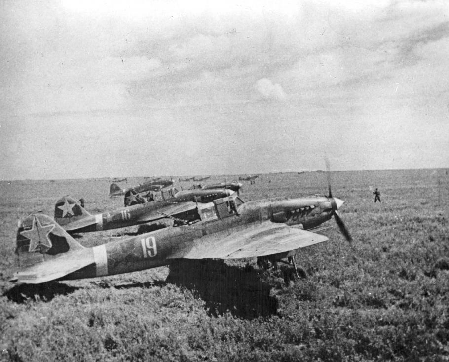 Historical photo of several aircraft on a grassy field. 