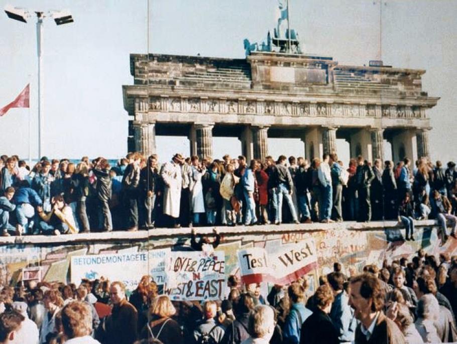 A crowd stands on the Berlin wall. 