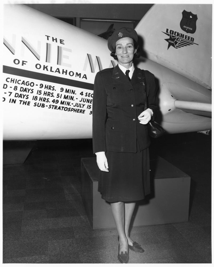 A woman in uniform stands at the side of an aircraft.