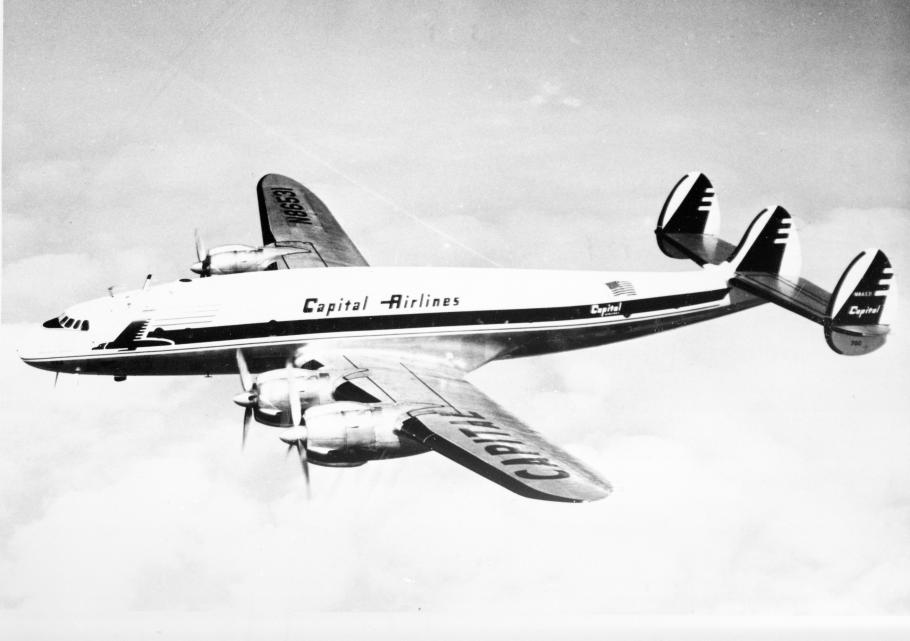 Side view of commercial aircraft in flight. Aircraft has four engines. Aircraft features "Capitol Airlines" name above the wings.