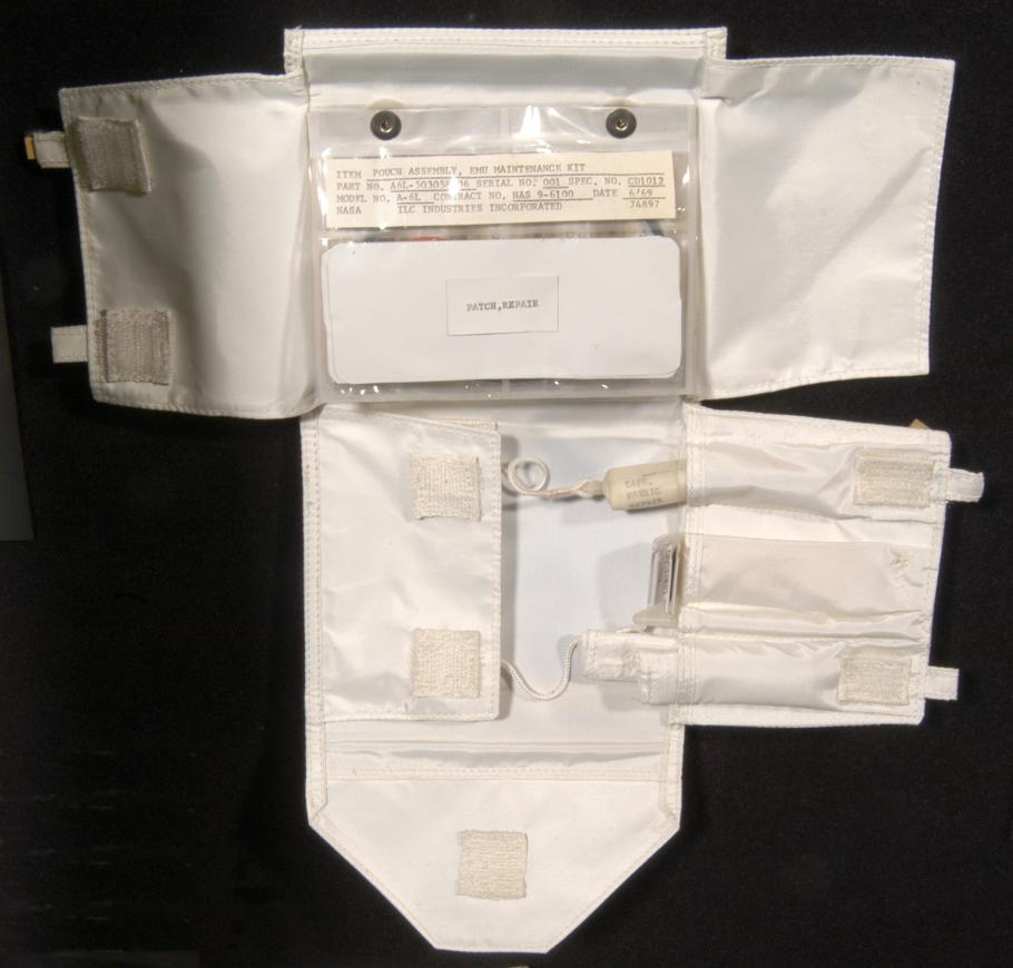 Small maintenance kit made with white fabric and velcro to keep items in place. Multiple items inside small plastic-like bag on upper layer, with three tools visble in a lower section.