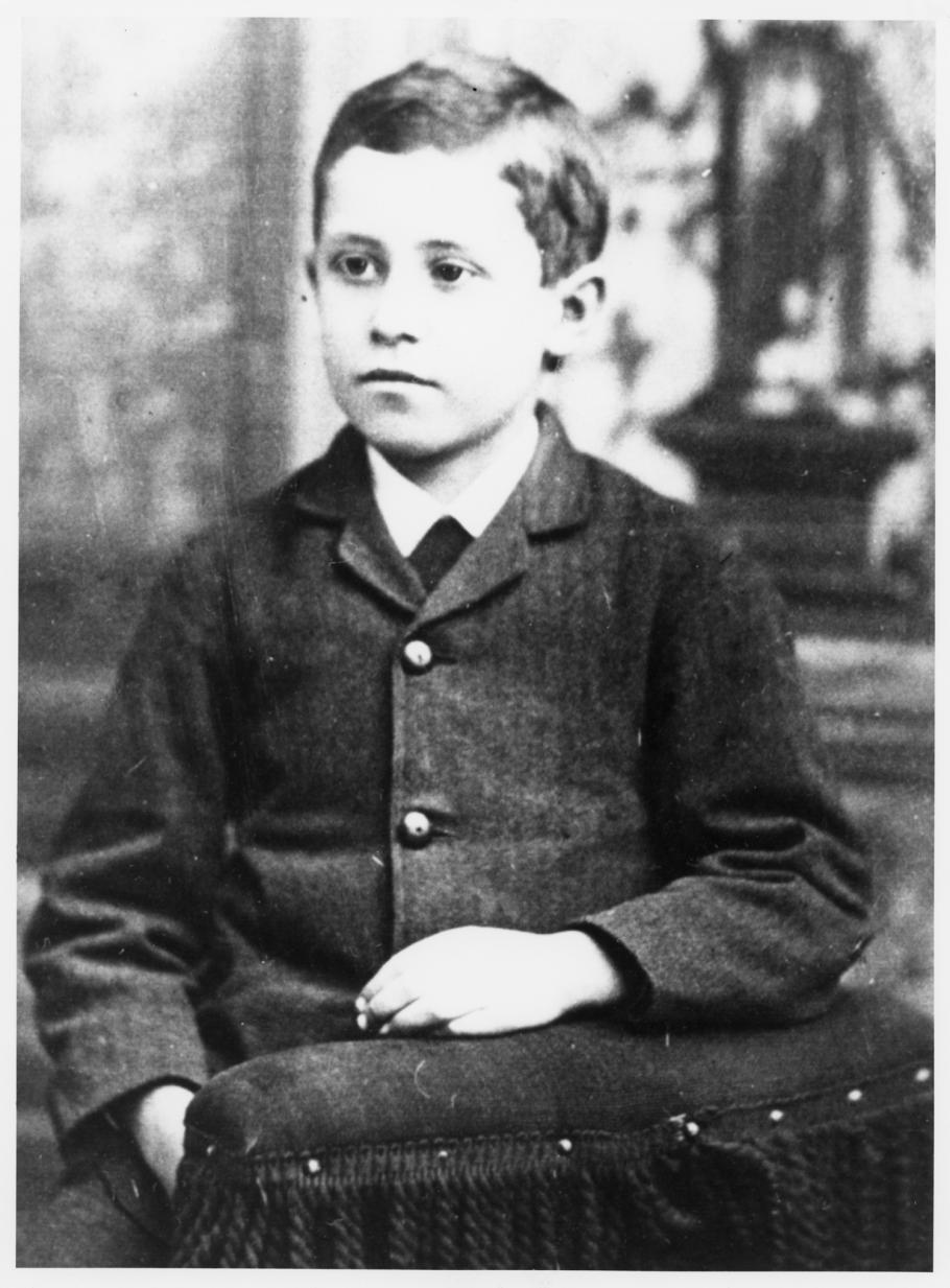 Black and white portrait of a boy sitting in a chair.