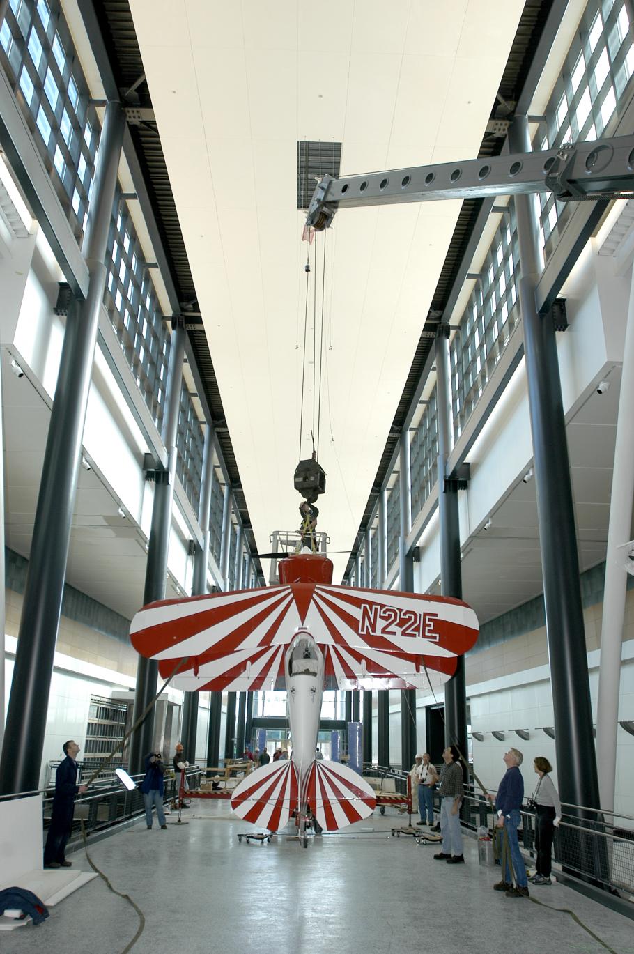 A red and white biplane is lifted into its display position above visitors at the Museum's Steven F. Udvar-Hazy Center.