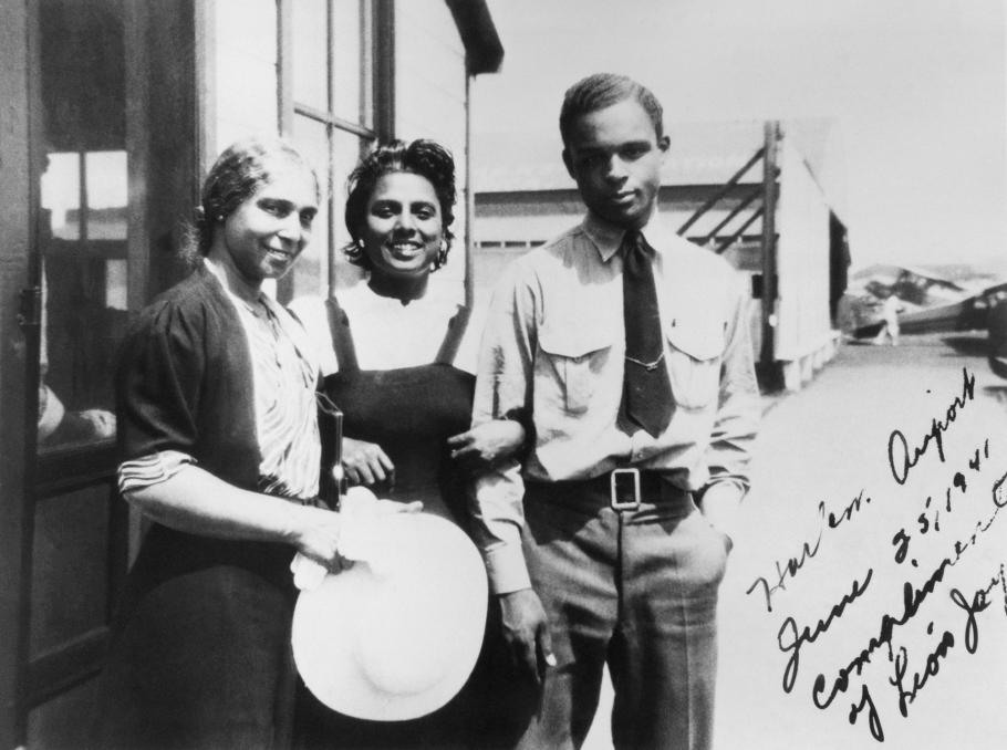 Three African-American people, including Willa Brown and Perry Young, stand together at an airport. 