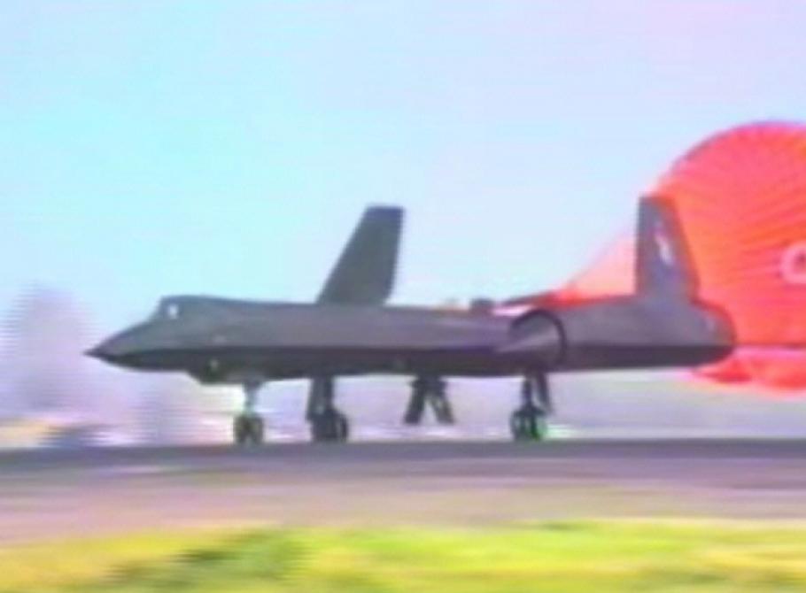 Blurry view of the SR-71, a gray-colored reconnaisance aircraft, during a landing. An orange-colored parachute is deployed in the rear of the aircraft.